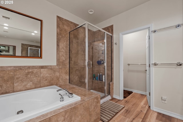 bathroom with hardwood / wood-style flooring and shower with separate bathtub