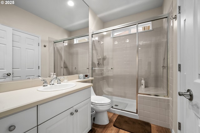 bathroom featuring toilet, vanity, a shower with door, and hardwood / wood-style floors