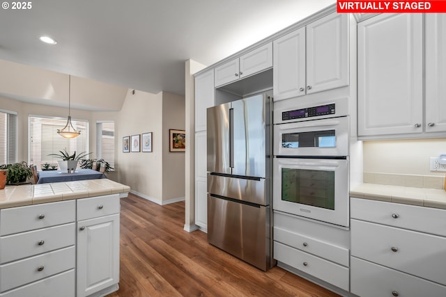 kitchen with tile countertops, white cabinets, white double oven, and stainless steel refrigerator