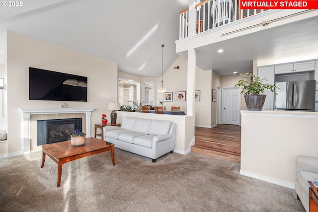 carpeted living room with a tiled fireplace and high vaulted ceiling