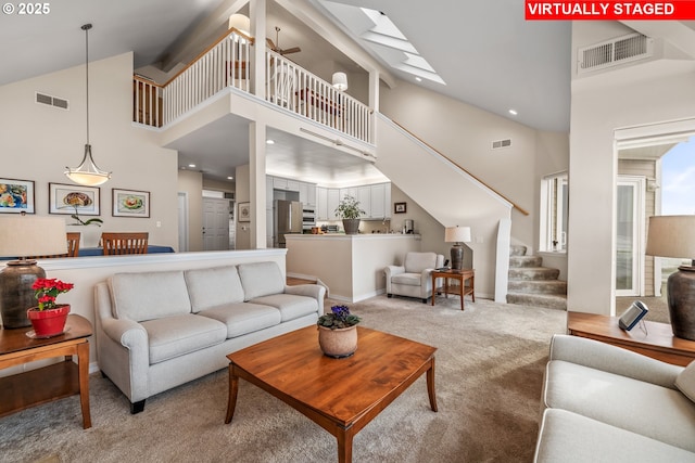 living room with ceiling fan, light carpet, and a towering ceiling