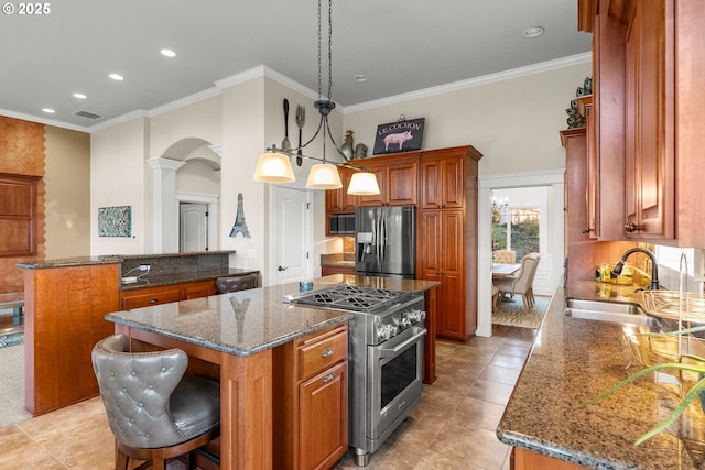 kitchen with stainless steel appliances, sink, decorative light fixtures, dark stone countertops, and a center island