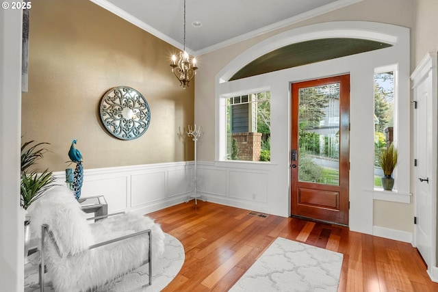 entryway with hardwood / wood-style flooring, a notable chandelier, and crown molding