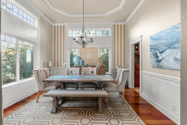 dining area featuring a chandelier, wood-type flooring, a tray ceiling, and ornamental molding