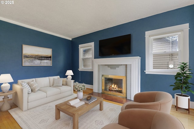 living room with a fireplace, a textured ceiling, and wood finished floors