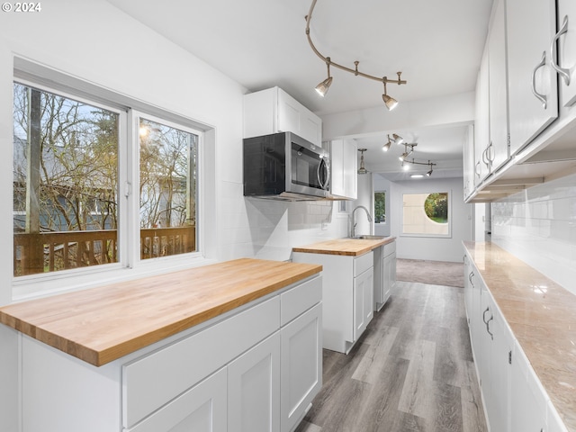 kitchen featuring wood counters, sink, white cabinetry, and backsplash