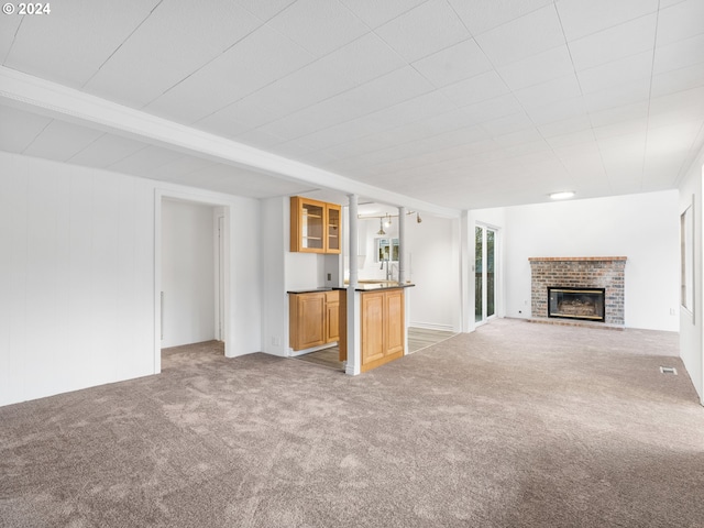 unfurnished living room with beamed ceiling, carpet, and a brick fireplace