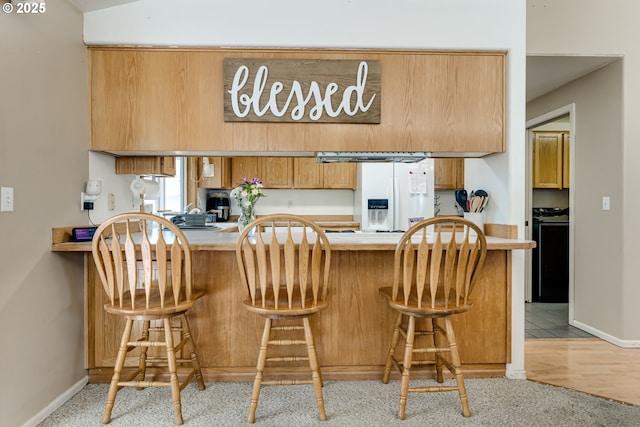 1278 Winery Ln, Eugene, OR 97404 - kitchen with white fridge with ice dispenser, a peninsula, light countertops, and baseboards