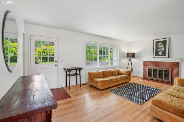 4242 SW Admiral St, Portland, OR 97221 - living area with light wood finished floors, a brick fireplace, and baseboards
