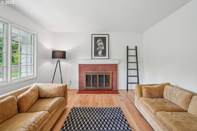 4242 SW Admiral St, Portland, OR 97221 - living area with light wood-type flooring, a brick fireplace, and baseboards