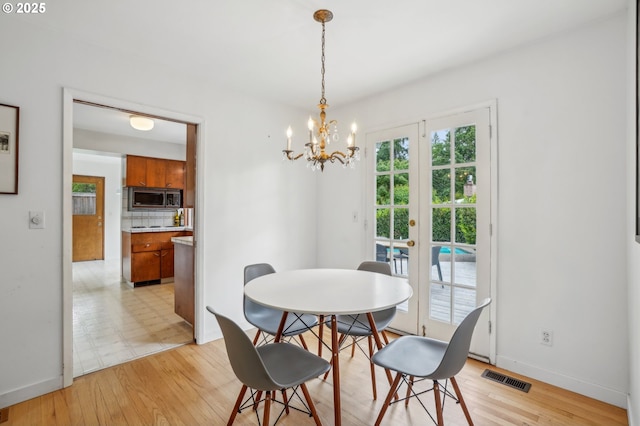 4242 SW Admiral St, Portland, OR 97221 - dining area featuring a chandelier, baseboards, light wood-type flooring, and french doors