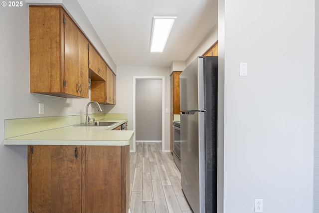 4004 Ginkgo Ave, Tillamook, OR 97141 - kitchen featuring freestanding refrigerator, a sink, baseboards, a peninsula, and light wood-style flooring