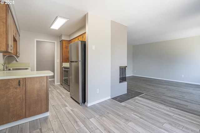4004 Ginkgo Ave, Tillamook, OR 97141 - kitchen featuring stainless steel appliances, a sink, light wood-style flooring, and brown cabinetry