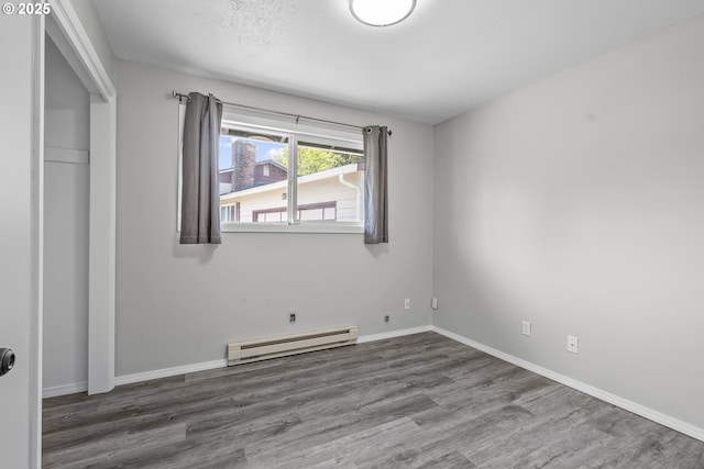 4004 Ginkgo Ave, Tillamook, OR 97141 - unfurnished bedroom featuring a baseboard heating unit, wood finished floors, and baseboards