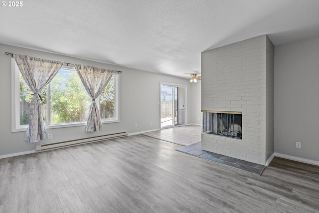4004 Ginkgo Ave, Tillamook, OR 97141 - unfurnished living room featuring baseboard heating, a brick fireplace, a textured ceiling, wood finished floors, and a ceiling fan
