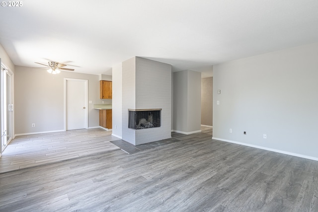 4004 Ginkgo Ave, Tillamook, OR 97141 - unfurnished living room with light wood-type flooring, baseboards, a ceiling fan, and a fireplace