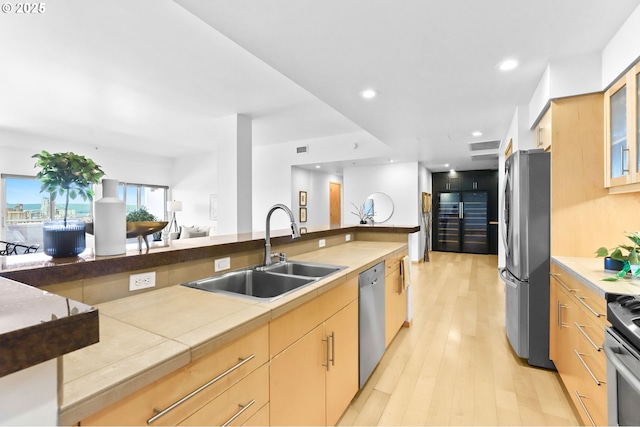 700 Washington St Unit 925, Vancouver, WA 98660 - kitchen with appliances with stainless steel finishes, a sink, light wood-style floors, glass insert cabinets, and light brown cabinets