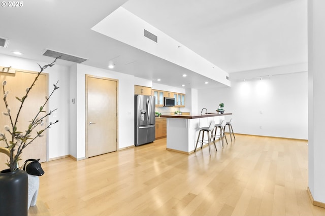 700 Washington St Unit 925, Vancouver, WA 98660 - kitchen featuring appliances with stainless steel finishes, a kitchen bar, light wood-type flooring, baseboards, and recessed lighting