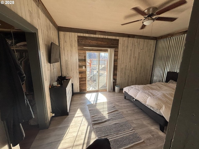 bedroom with hardwood / wood-style flooring, a closet, ceiling fan, and wood walls