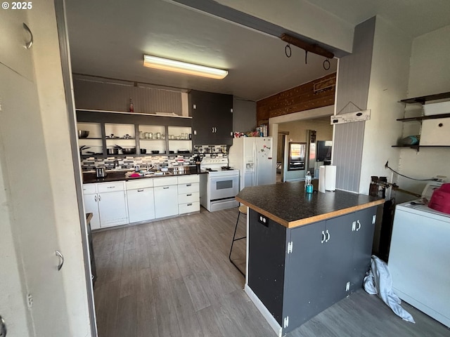 kitchen with tasteful backsplash, wood-type flooring, a kitchen breakfast bar, and white appliances