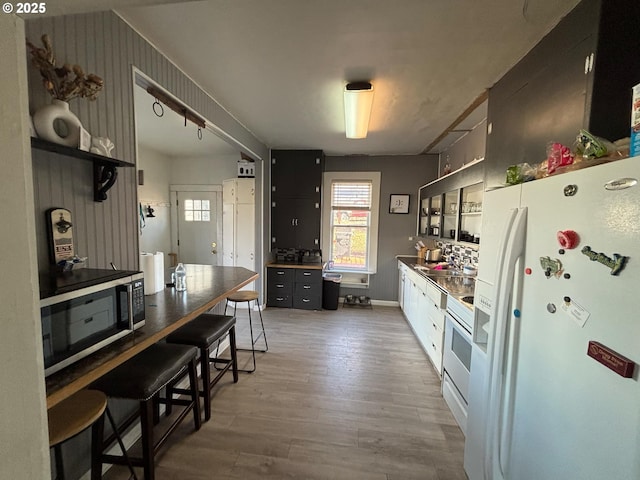 kitchen with sink, white appliances, dark wood-type flooring, and a breakfast bar