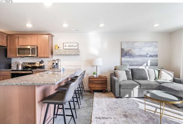 843 NE 11th St, Hermiston, OR 97838 - kitchen featuring stainless steel appliances, a sink, a kitchen breakfast bar, light stone countertops, and a peninsula