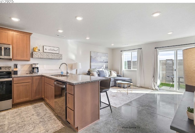 843 NE 11th St, Hermiston, OR 97838 - kitchen with stainless steel appliances, a peninsula, a sink, open floor plan, and light stone countertops