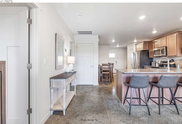 843 NE 11th St, Hermiston, OR 97838 - kitchen with appliances with stainless steel finishes, recessed lighting, a kitchen bar, light stone counters, and a peninsula