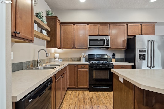 kitchen with sink, black appliances, light hardwood / wood-style floors, and a textured ceiling