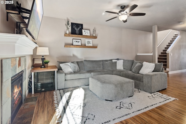 living room with dark wood-type flooring, a tile fireplace, and ceiling fan