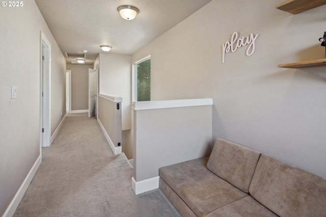 hallway featuring light carpet and a textured ceiling