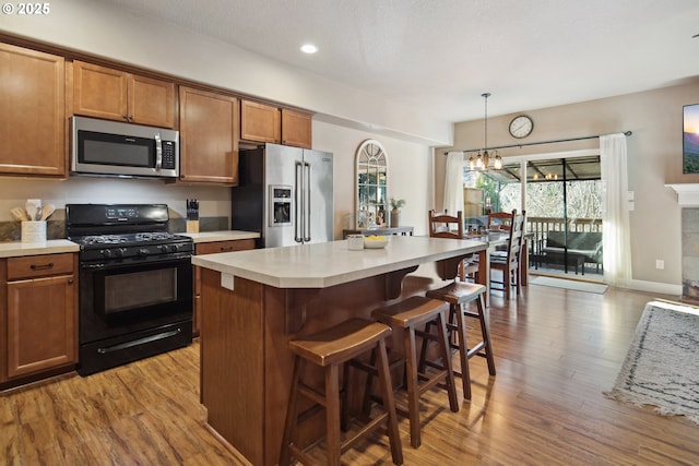 kitchen with a kitchen island, appliances with stainless steel finishes, pendant lighting, and light wood-type flooring