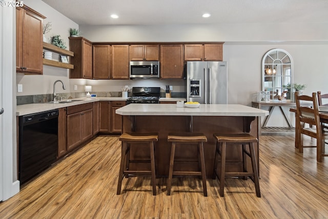 kitchen featuring a center island, sink, light hardwood / wood-style flooring, and black appliances