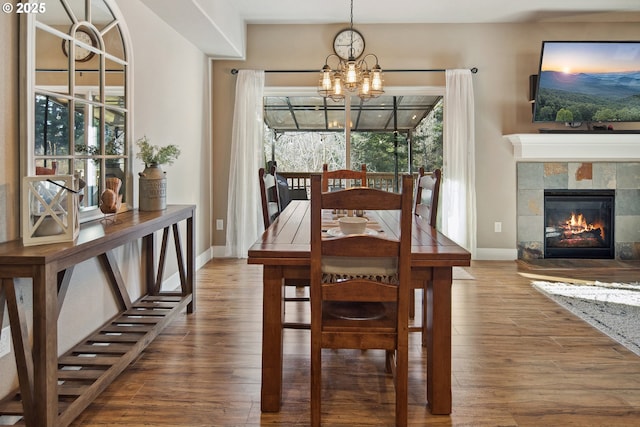 dining area featuring an inviting chandelier, hardwood / wood-style floors, and a fireplace