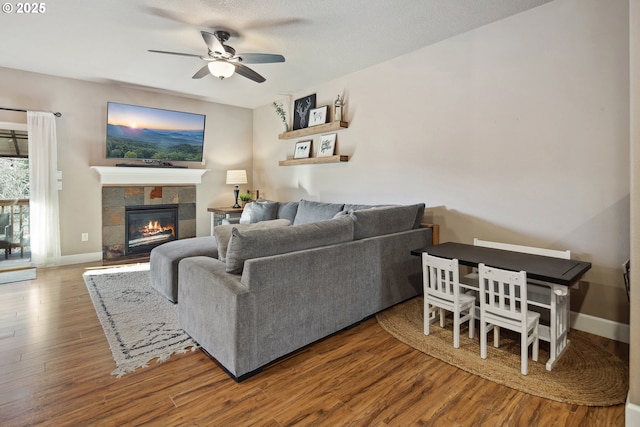 living room with ceiling fan, wood-type flooring, a fireplace, and a textured ceiling