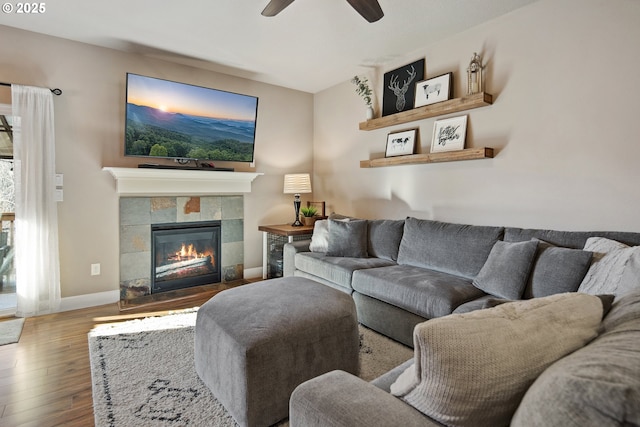 living room featuring a tile fireplace, wood-type flooring, and ceiling fan