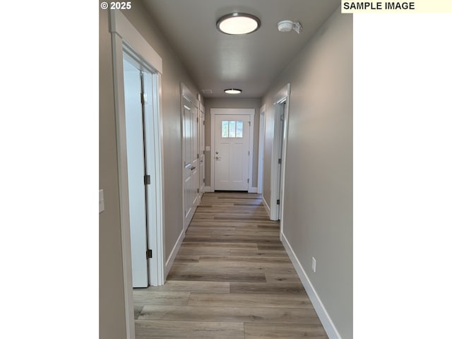 corridor with light wood-style flooring and baseboards