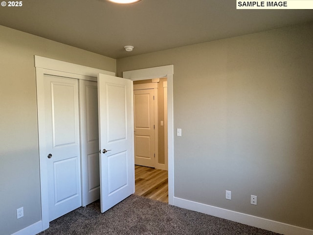 unfurnished bedroom featuring carpet floors, baseboards, and a closet