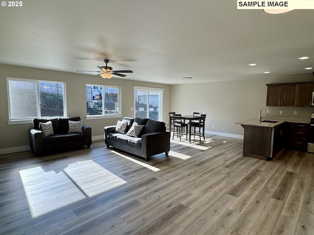 living room with baseboards, recessed lighting, a wealth of natural light, and light wood-style floors