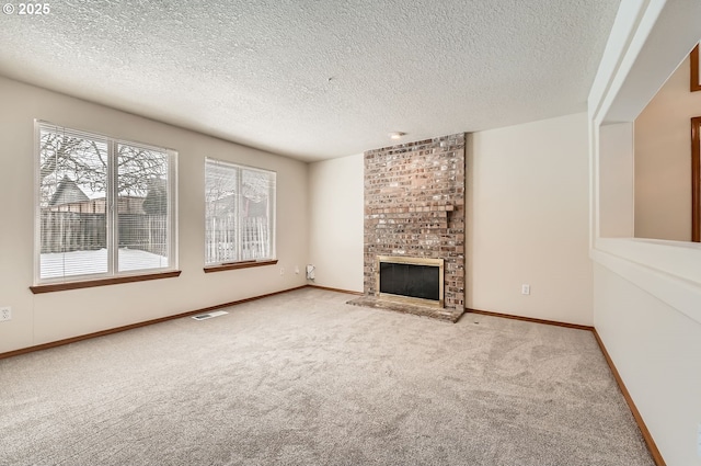 unfurnished living room with a brick fireplace, a textured ceiling, and light colored carpet