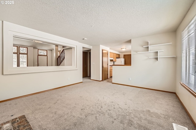 unfurnished living room with a textured ceiling, light carpet, and a healthy amount of sunlight