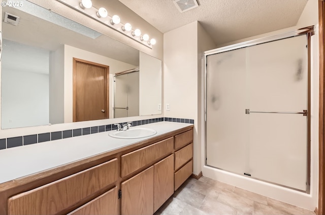 bathroom featuring vanity, an enclosed shower, and a textured ceiling