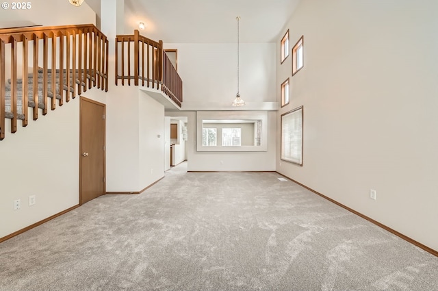 unfurnished living room featuring carpet flooring and a high ceiling