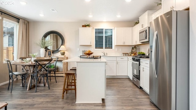 kitchen featuring a breakfast bar area, white cabinetry, a center island, dark hardwood / wood-style floors, and stainless steel appliances