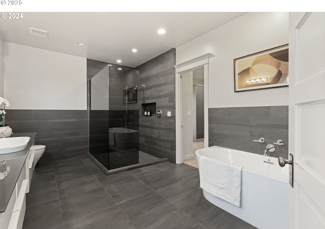 full bathroom featuring toilet, tile walls, vanity, plus walk in shower, and tile patterned flooring