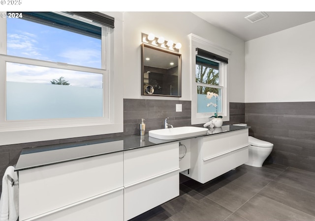 bathroom with tile patterned floors, vanity, toilet, and tile walls