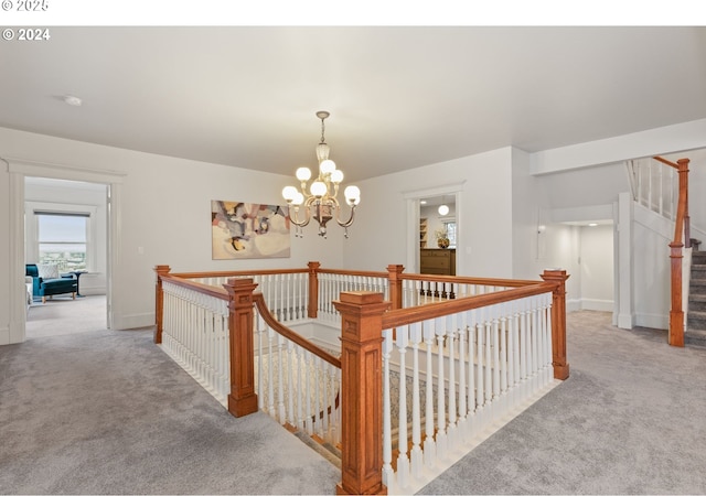 hall with an inviting chandelier and carpet floors