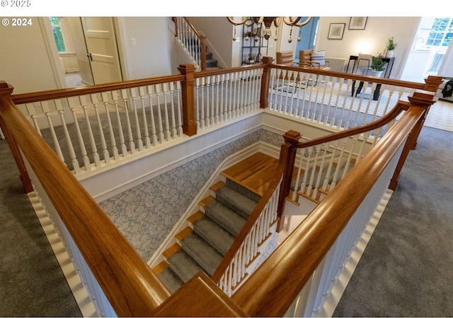 stairway featuring a notable chandelier and carpet flooring