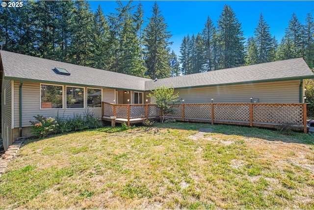 exterior space featuring a wooden deck, roof with shingles, and a yard