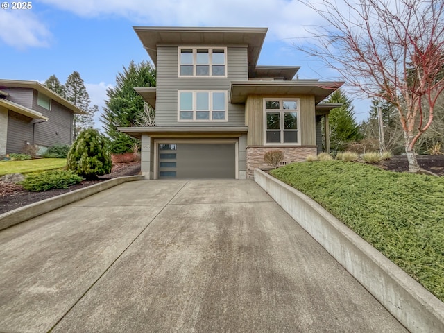 prairie-style house with concrete driveway, a garage, and stone siding